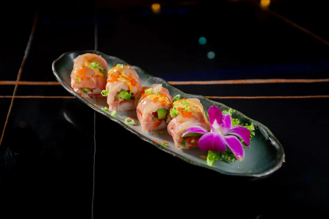 Plated sushi on a dark table, lit low and hard for a product shoot