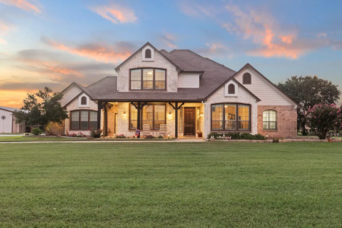 Twilight exterior of a brick North Texas home with the lawn and windows lit